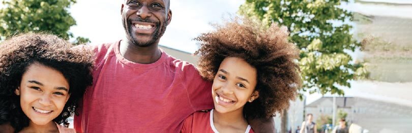 Father or caring adult smiling with his two daughters